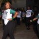 Gator girls 50 years: dancers in matching shirts perform outdoors, led by a woman posing with one hand on her hip.