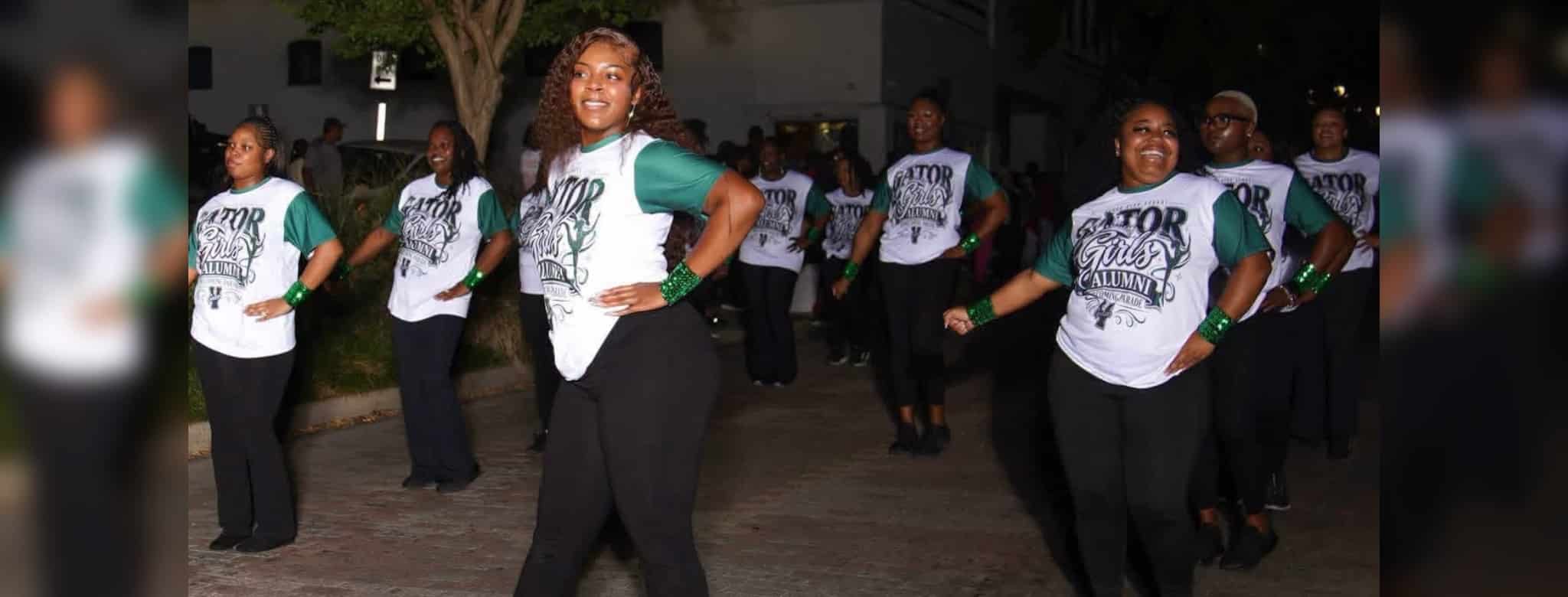 Gator girls 50 years: dancers in matching shirts perform outdoors, led by a woman posing with one hand on her hip.