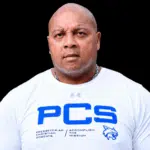 William Prince, a former athlete, wearing a white shirt with PCS logo, looking serious and confident.
