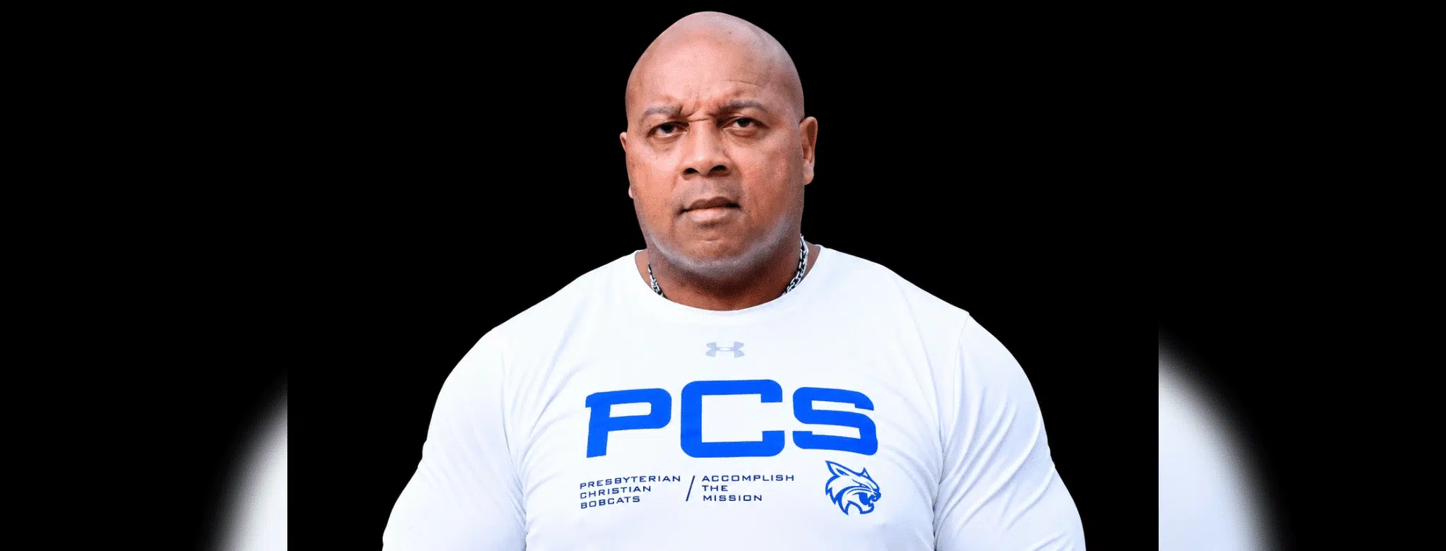 William Prince, a former athlete, wearing a white shirt with PCS logo, looking serious and confident.