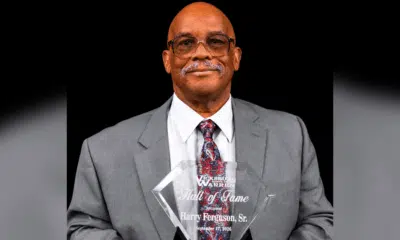 Harry Ferguson Sr. holding his Hall of Fame award, dressed in a gray suit with a patterned tie.