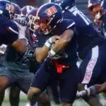 Jackson State player running with the ball during a football game against Alabama A&M, showcasing team spirit and — 31-28