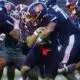 Jackson State player running with the ball during a football game against Alabama A&M, showcasing team spirit and — 31-28