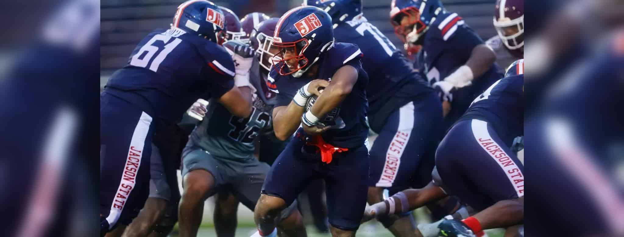 Jackson State player running with the ball during a football game against Alabama A&M, showcasing team spirit and — 31-28