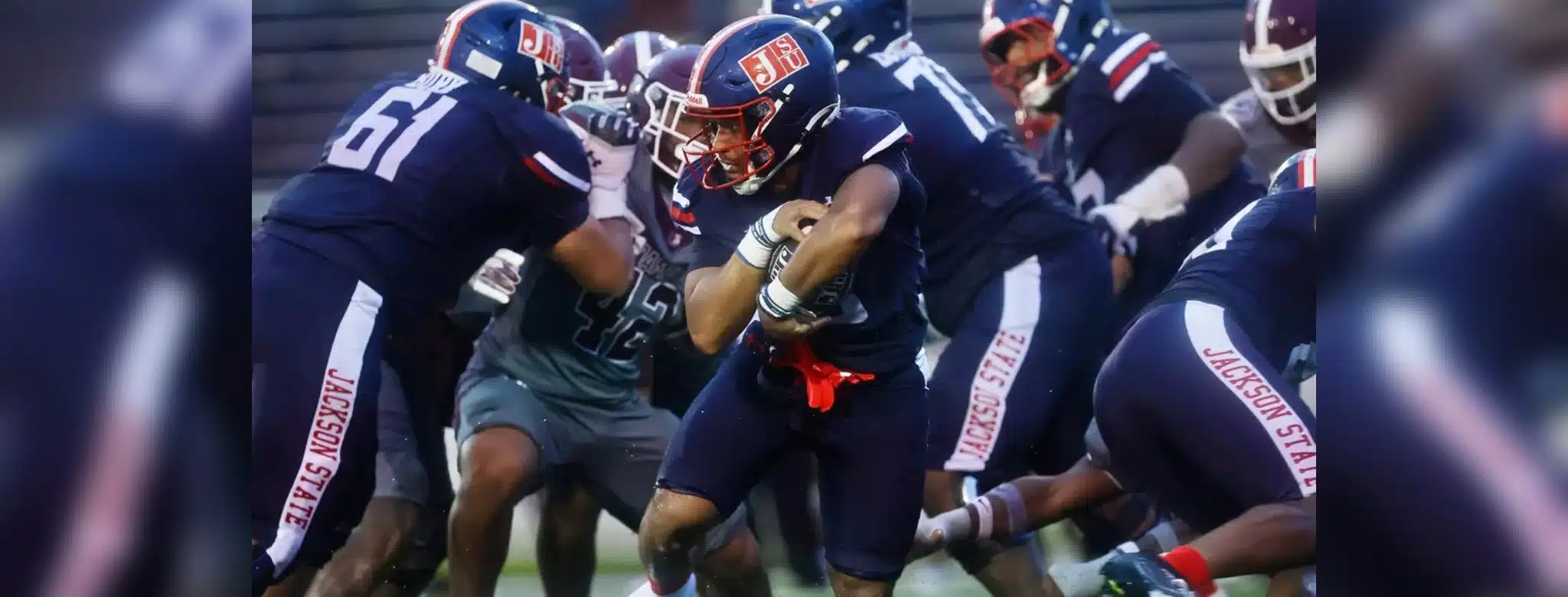 Jackson State player running with the ball during a football game against Alabama A&M, showcasing team spirit and — 31-28