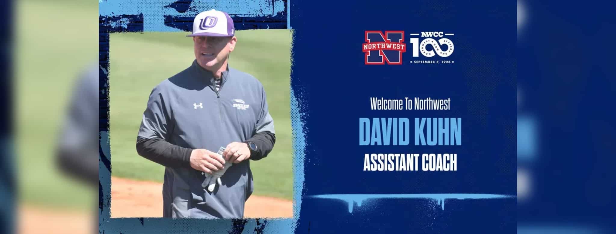 David Kuhn in a gray jacket and baseball cap, smiling on a softball field.