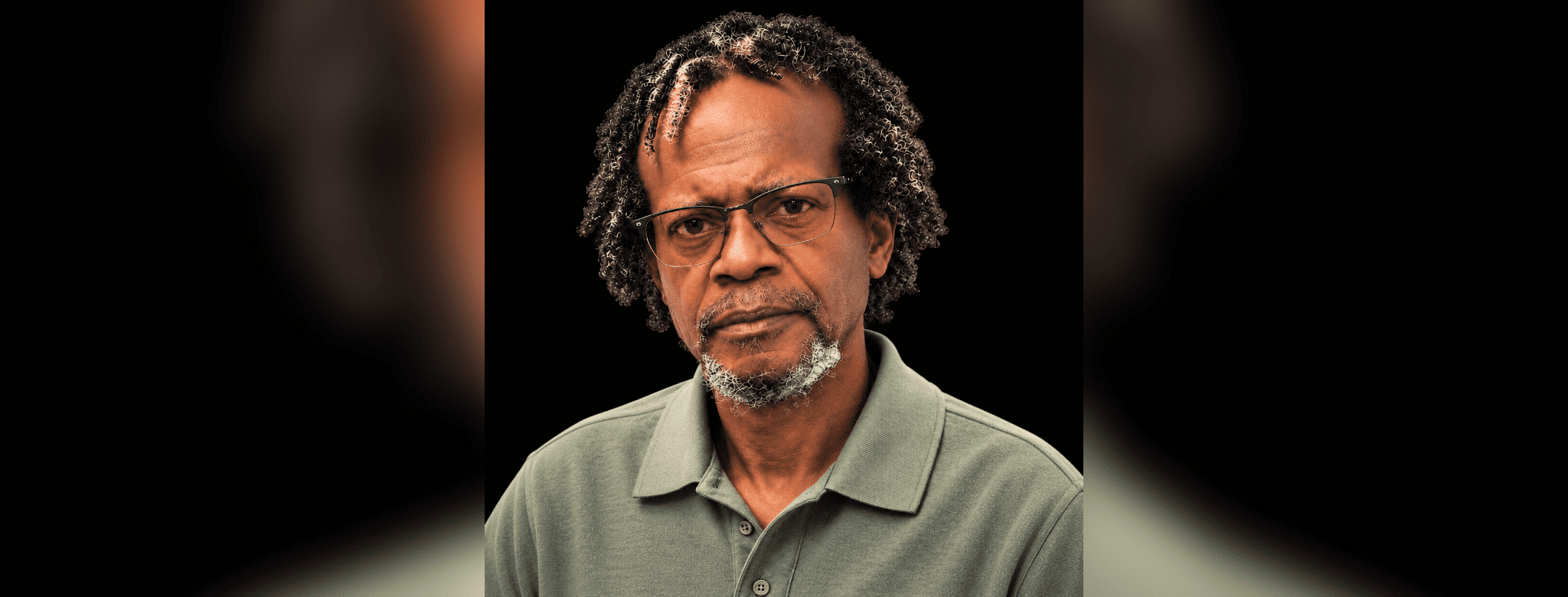 A serious-looking man with glasses and curly hair, wearing a green polo shirt. — Leroy Newton