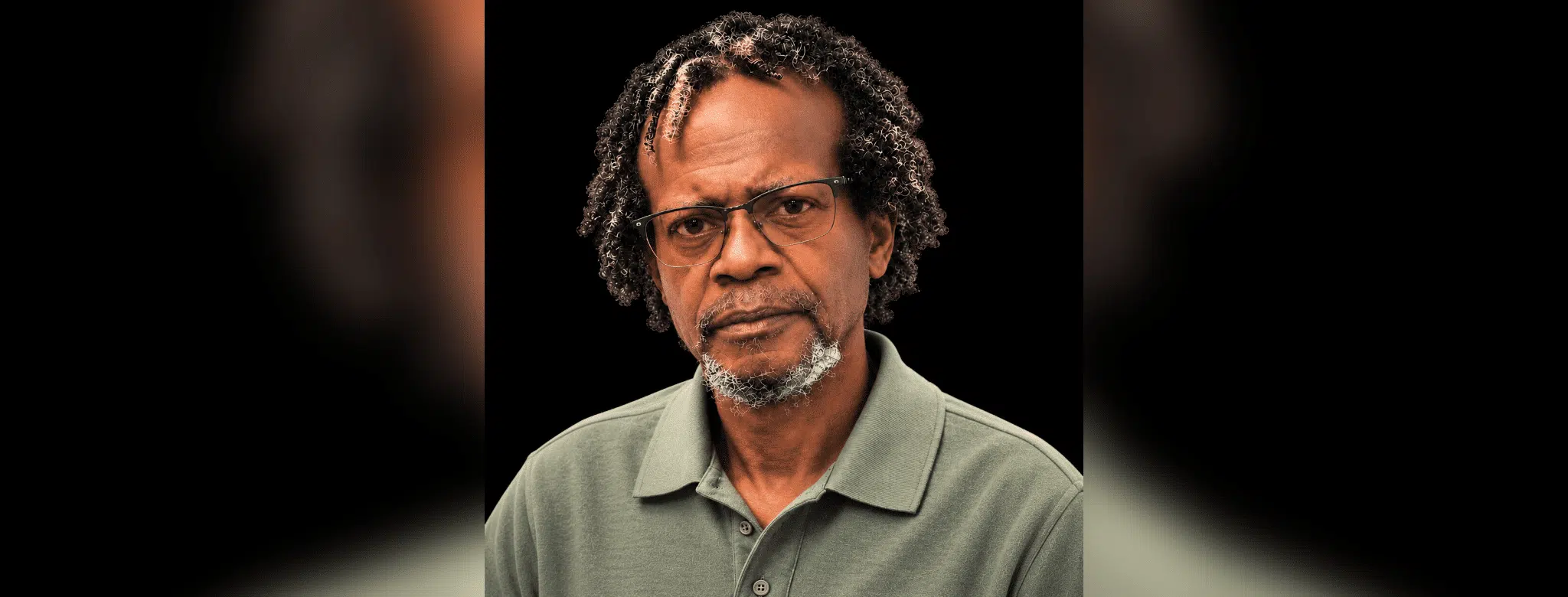 A serious-looking man with glasses and curly hair, wearing a green polo shirt. — Leroy Newton