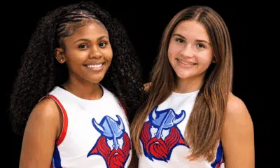 Two young cheerleaders smiling, wearing cheer uniforms with a Viking logo, celebrating their roles as cheer captains.