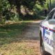 Police car with lights on near a wooded area where a person is seated on the ground, indicating a shoo — Shot in Vicksburg