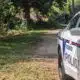 Police car with lights on near a wooded area where a person is seated on the ground, indicating a shoo — Shot in Vicksburg