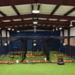 Interior view of a new indoor training facility with batting cages and turf flooring for student-athletes.