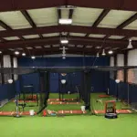 Interior view of a new indoor training facility with batting cages and turf flooring for student-athletes.