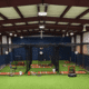 Interior view of a new indoor training facility with batting cages and turf flooring for student-athletes.