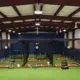 Interior view of a new indoor training facility with batting cages and turf flooring for student-athletes.