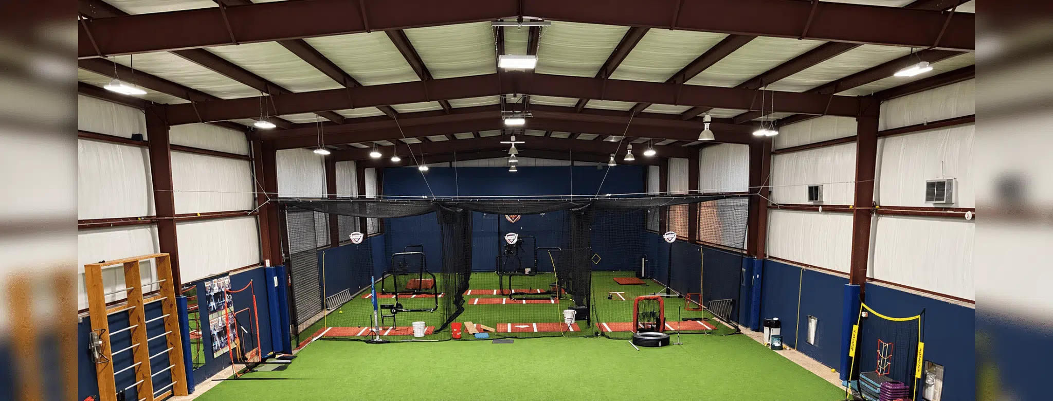 Interior view of a new indoor training facility with batting cages and turf flooring for student-athletes.