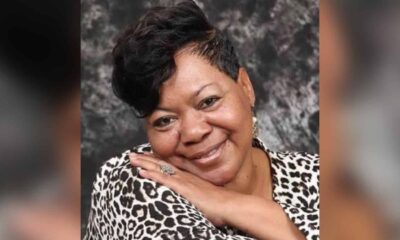 Smiling woman with short hair and a leopard print top, resting her chin on her hand against a textured background. — Verna