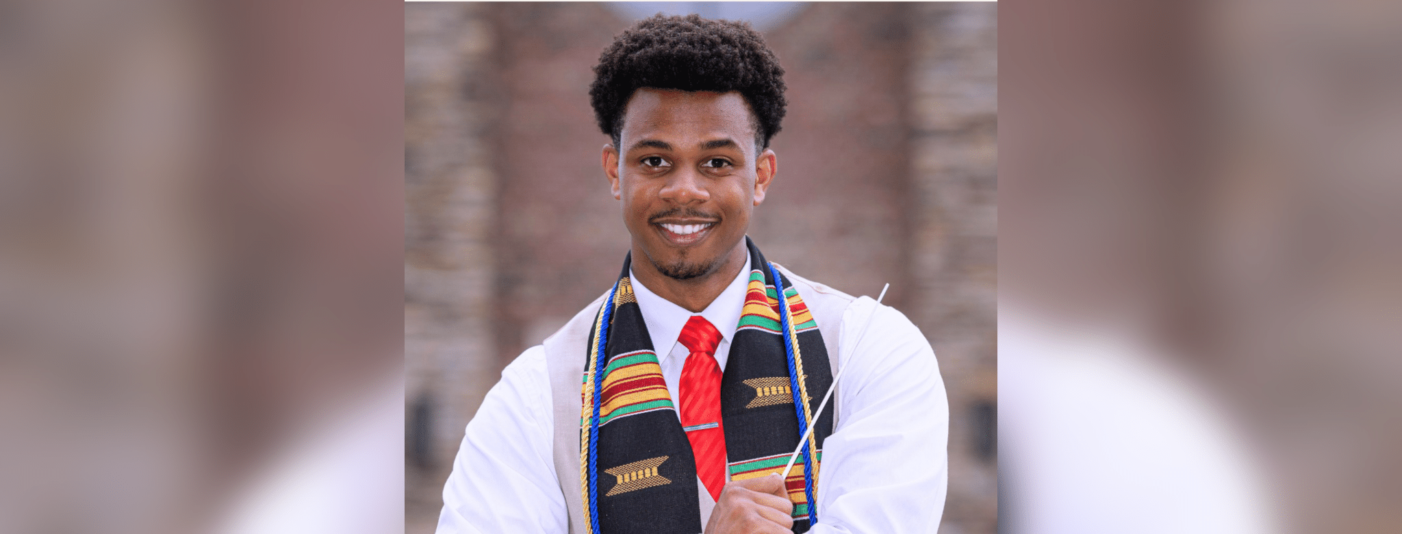 Kameren Batty smiles in a white shirt, red tie and colorful stole.