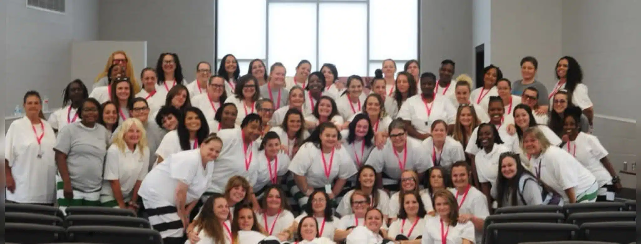 Group photo of 39 women inmates in white shirts celebrating graduation from a rehabilitation program.