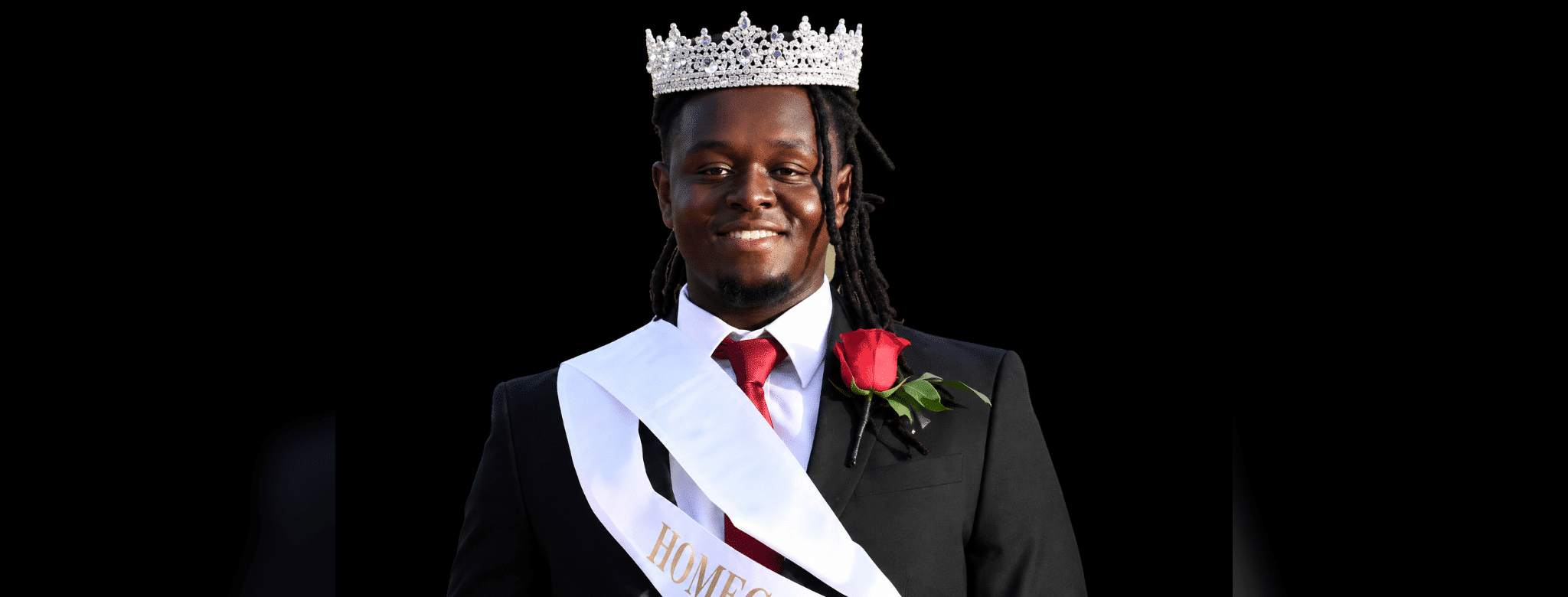 Mason Watts wearing a crown and sash, smiling proudly at his Homecoming King coronation. — Mason Watts homecoming king