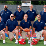 Warren Central football coaches pose on the field with helmets as the Vikings playoff season continues.