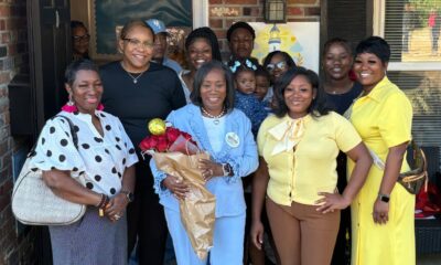 Group of people celebrating the opening of Guiding Light Early Learning Center with Sylvia Brown at the center holding flo…