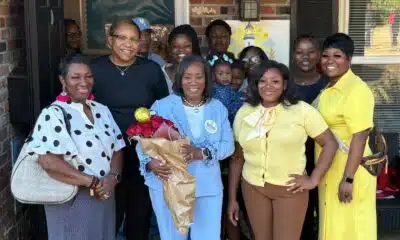Group of people celebrating the opening of Guiding Light Early Learning Center with Sylvia Brown at the center holding flo…