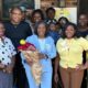 Group of people celebrating the opening of Guiding Light Early Learning Center with Sylvia Brown at the center holding flo…