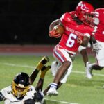 Warren Central player in red jersey evades a tackle during a football game against Greenville, showcasin — 45-6 homecoming