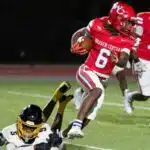 Warren Central player in red jersey evades a tackle during a football game against Greenville, showcasin — 45-6 homecoming