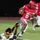 Warren Central player in red jersey evades a tackle during a football game against Greenville, showcasin — 45-6 homecoming