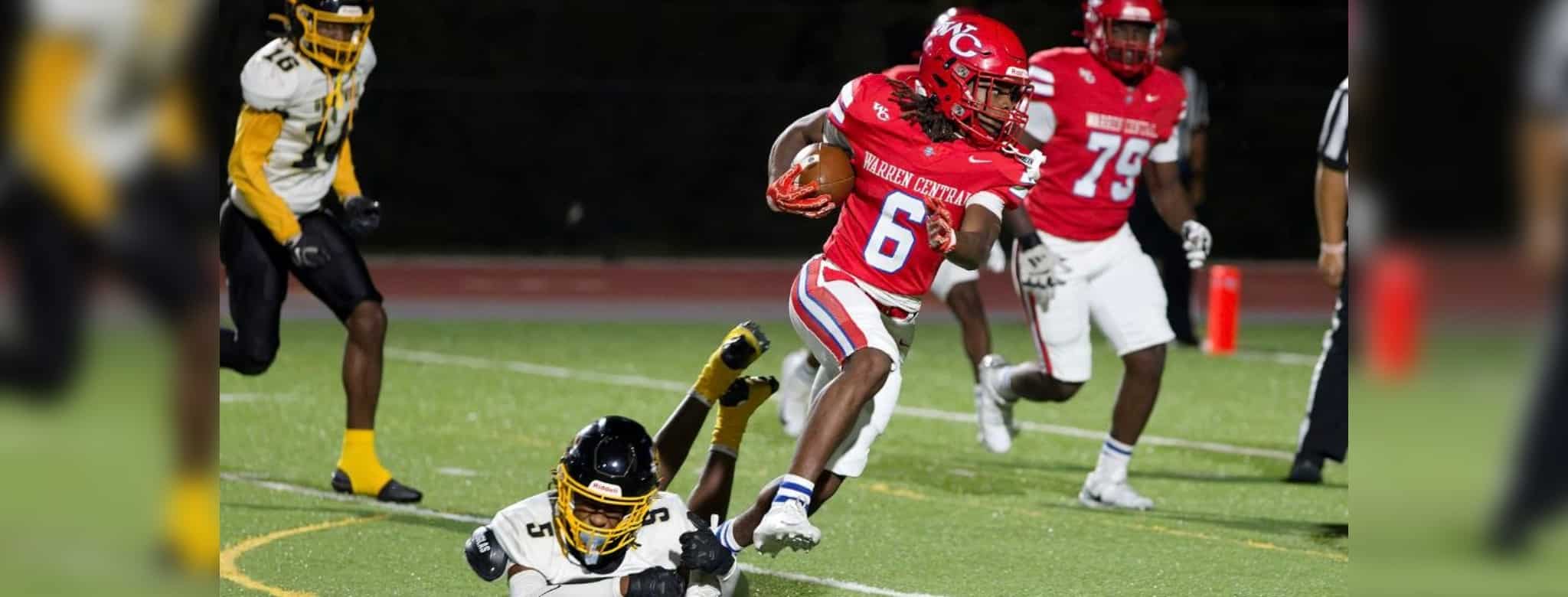 Warren Central player in red jersey evades a tackle during a football game against Greenville, showcasin — 45-6 homecoming