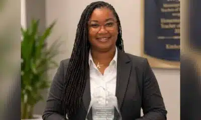 Kimberley King smiles in a dark blazer and white blouse, holding an award plaque.