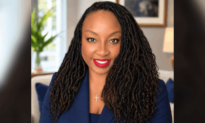 Portrait of Dr. Kim Carter Evans with long braided hair, wearing a navy blazer and red lipstick, smiling confidently.