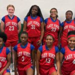 Warren Central Junior girls basketball players pose in red Lady Vikes uniforms inside a gym.
