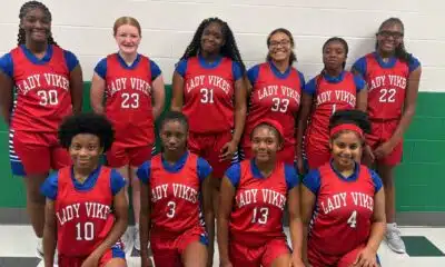 Warren Central Junior girls basketball players pose in red Lady Vikes uniforms inside a gym.