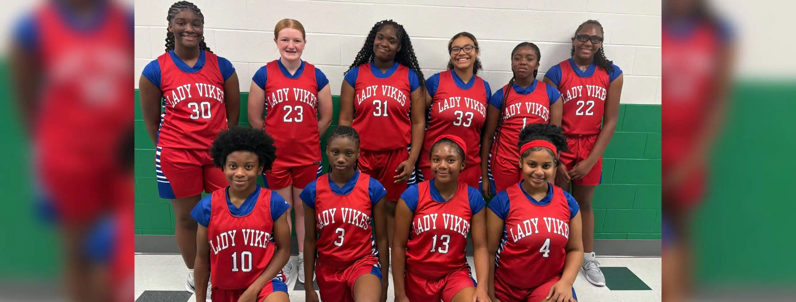 Warren Central Junior girls basketball players pose in red Lady Vikes uniforms inside a gym.