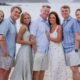 The Larsen family stands together on a beach, smiling in summer clothing.