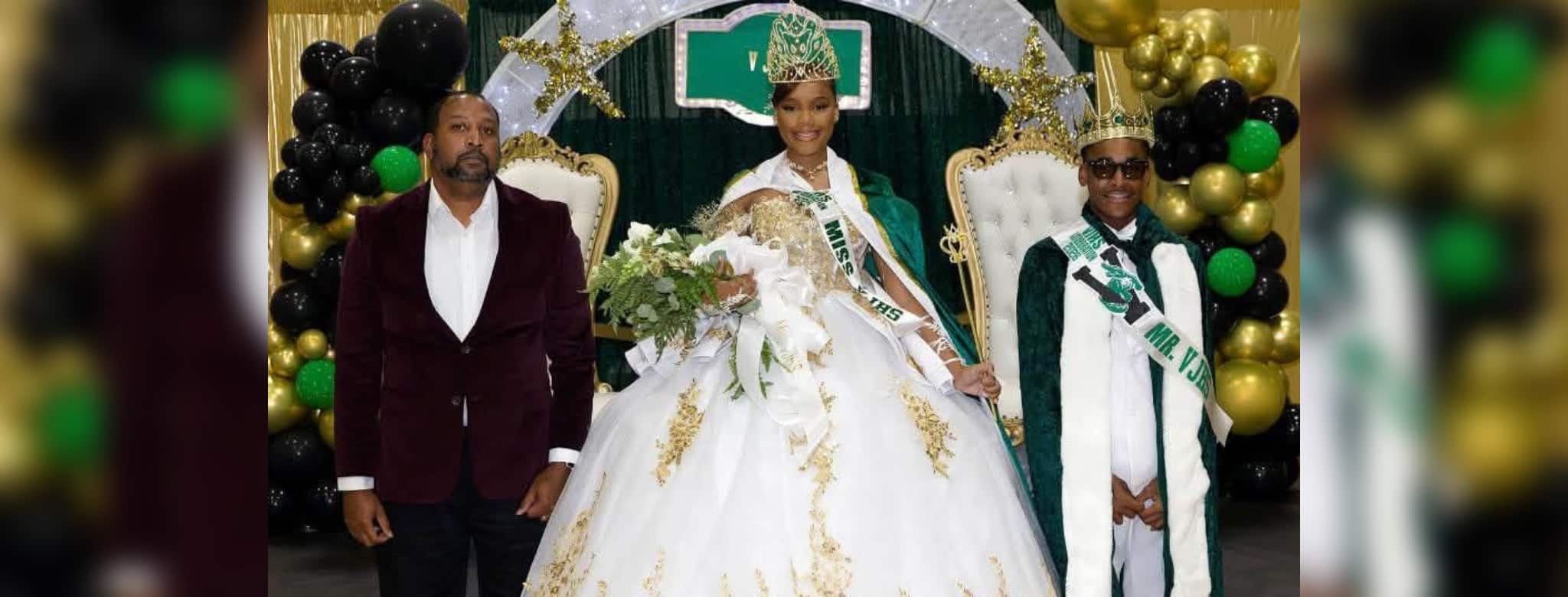 Gatotbration ceremony display with a student in a white gown and crown between two adults, amid black and gold balloons
