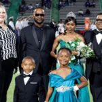 To’Nia Taylor homecoming queen in a turquoise gown poses with family members on the football field.