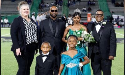 To’Nia Taylor homecoming queen in a turquoise gown poses with family members on the football field.