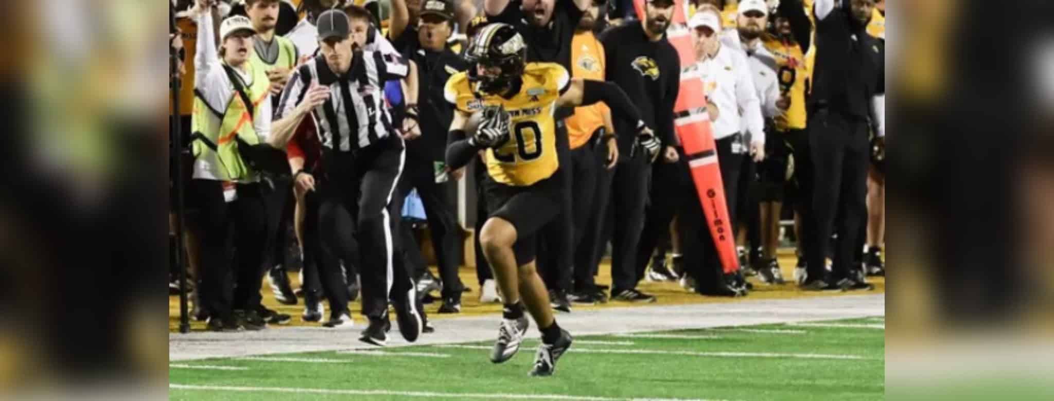 Southern Miss player in a black and gold uniform runs with the football as officials and sideline staff watch — Lafayette
